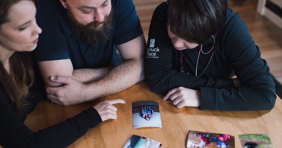 Father and mother with Canuck Place nurse practitioner looking at photos